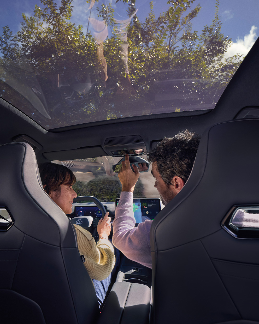 Aufnahme von einer Frau und einem Mann sitzend im Fahrzeug. Die Frau am Steuer, der Mann bedient das Modul oben im Innenraum des Fahrzeugs. 