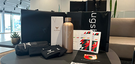 CUPRA Geschenkset mit Trinkflasche, Merchandise-Artikeln und FC Augsburg Fanartikeln auf einem Tisch im Autohaus