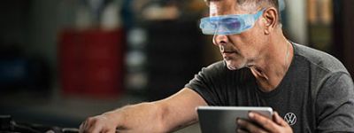 Mitarbeiter des digitalen Service der VGRD, schaut in Motorraum und h&auml;lt ein Tablet in der Hand